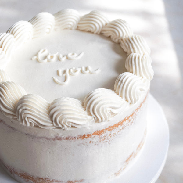 Weißer veganer semi-naked Cake mit Cremedeko und Schriftzug