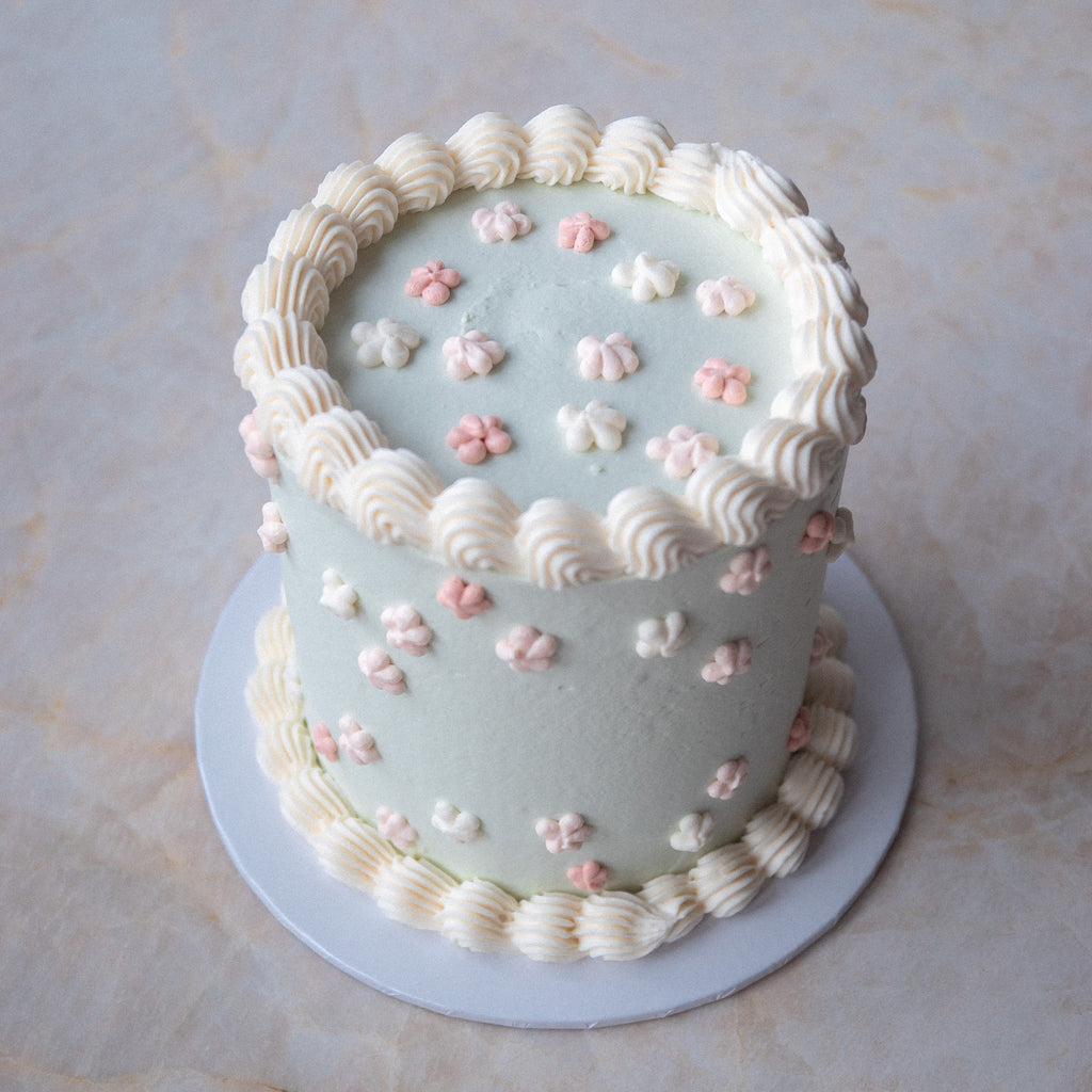 Hellgrüne vegane Torte mit kleinen Cremeblümchen